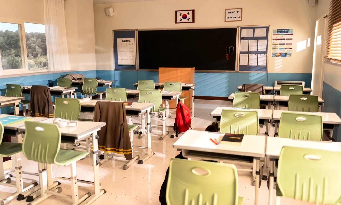The classroom set with light-green chairs and desks, a blackboard and a Korean flag